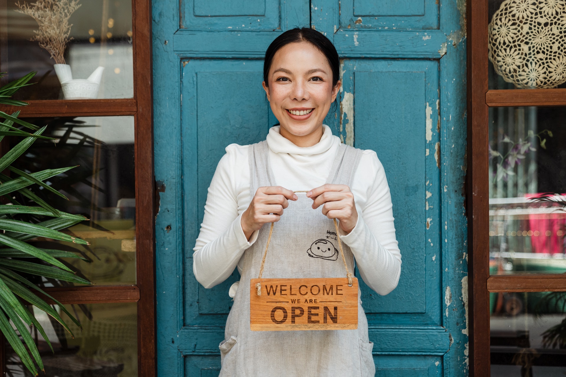 Business owner holding a Welcome We Are Open Sign